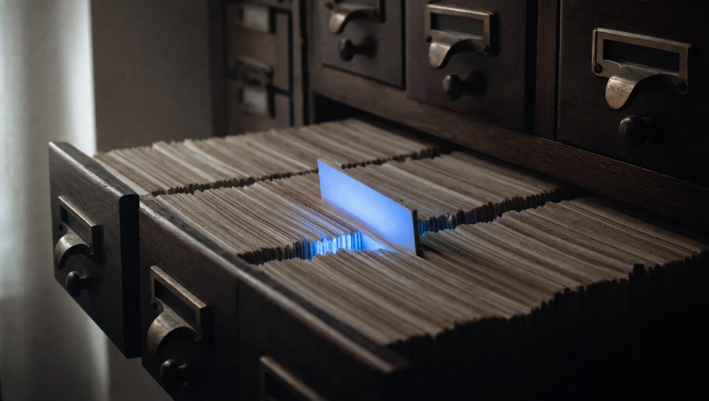 Un cajón de archivo con fichas, una de ellas levantada por encima de la fila